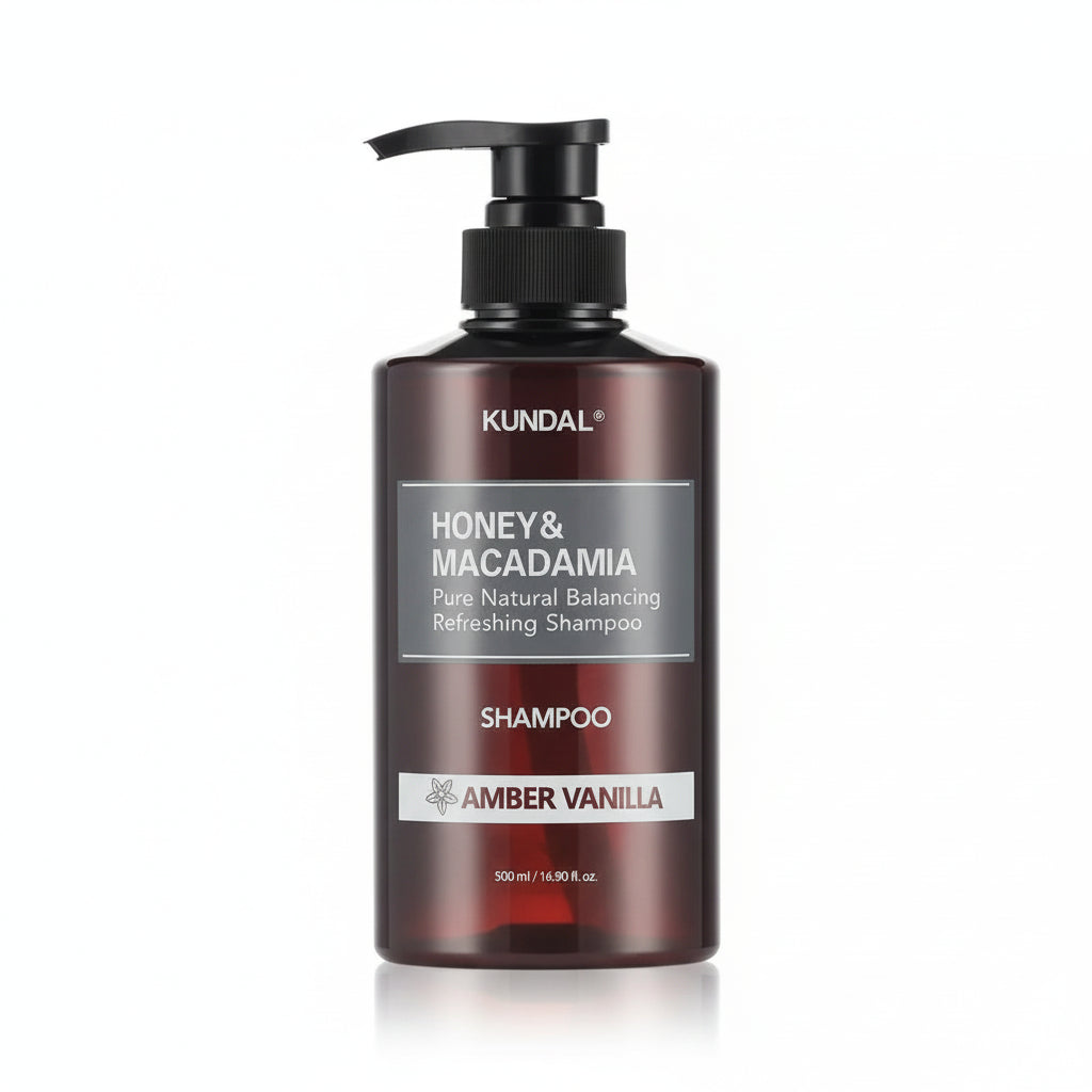 A 500 ml pump bottle of KUNDAL Honey & Macadamia Baby Powder Shampoo, featuring a dark brown translucent bottle, black pump dispenser, and silver and white labels, set against a plain white background.